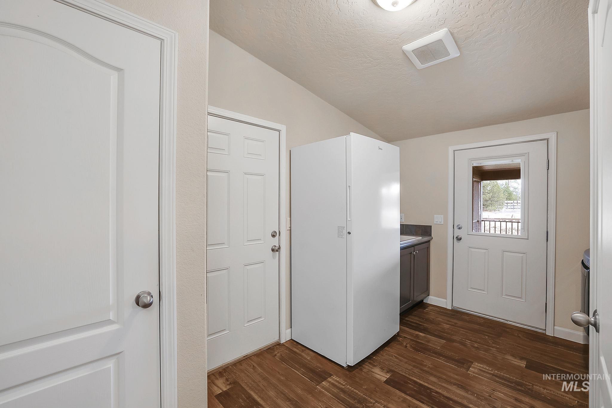 Washroom featuring a textured ceiling, vaulted ceiling, and dark wood-style flooring