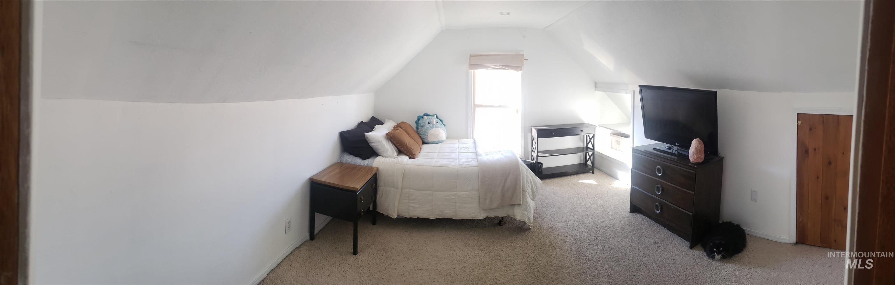 Bedroom with vaulted ceiling and light carpet