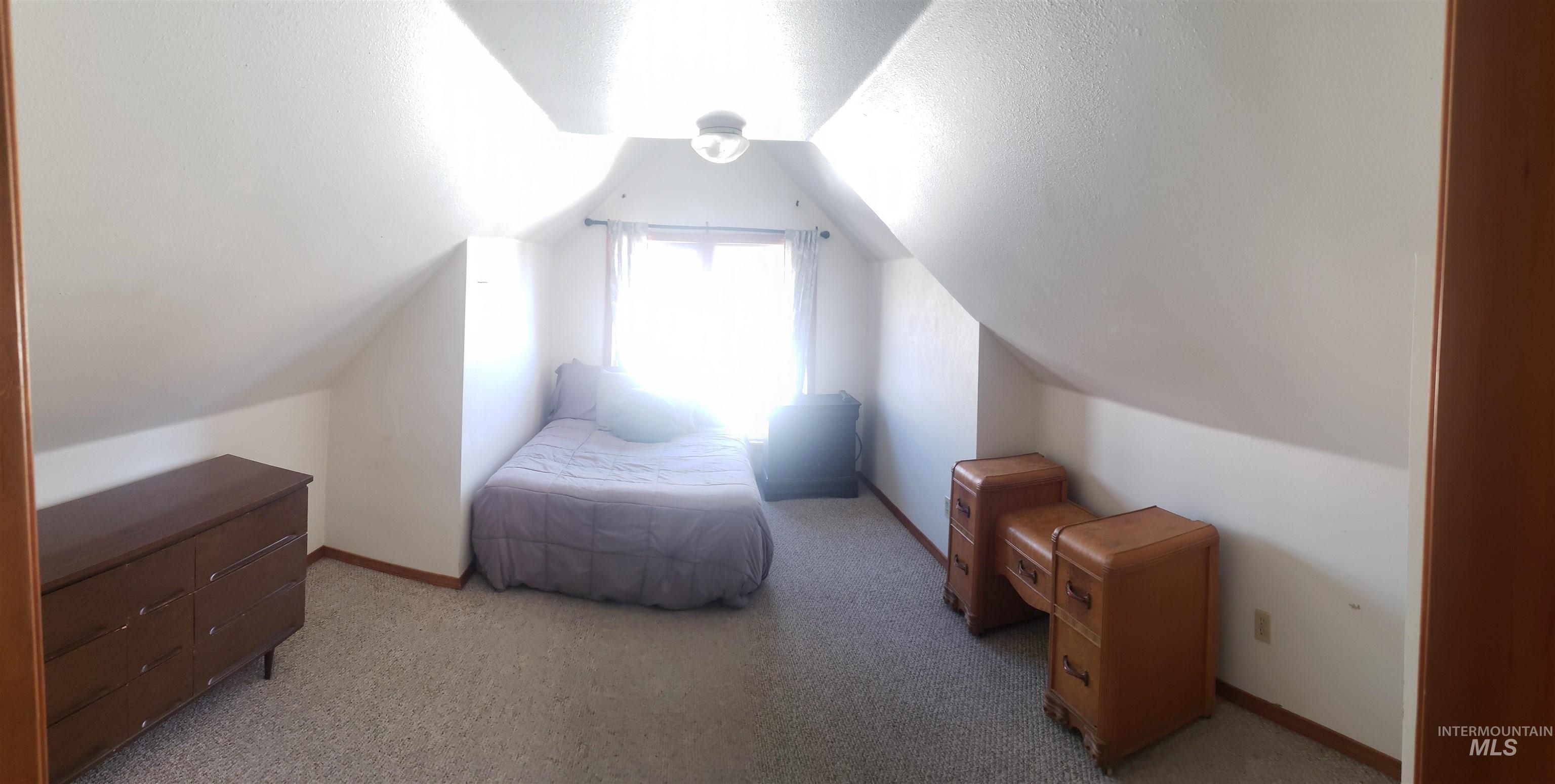 Bedroom with vaulted ceiling, a textured ceiling, and light carpet