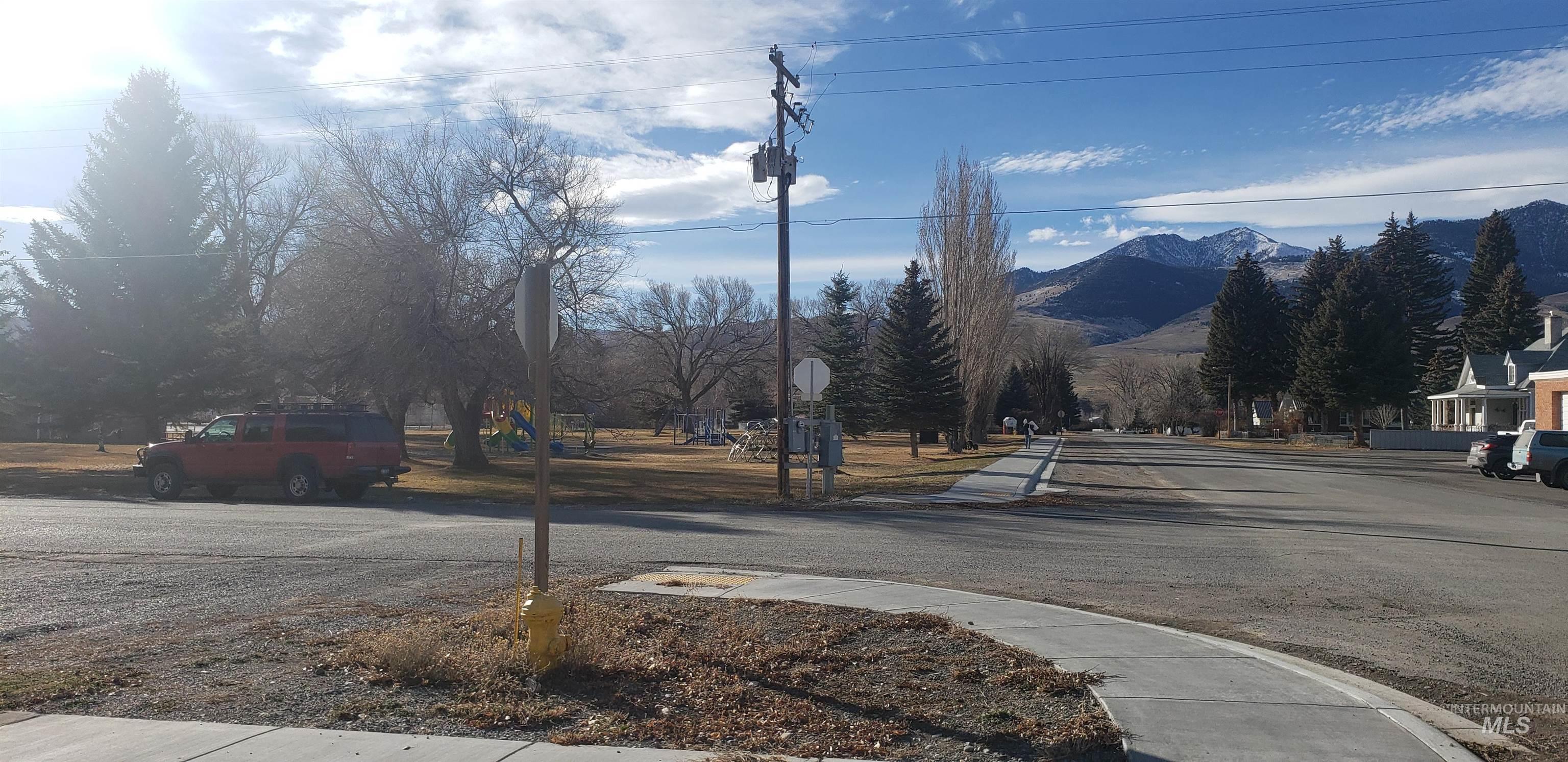View of asphalt street featuring sidewalks, a mountain view, and traffic signs
