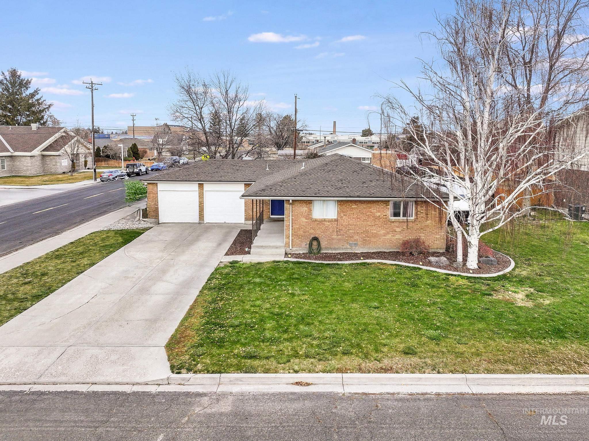 Single story home with brick siding, driveway, a shingled roof, a front yard, and a residential view