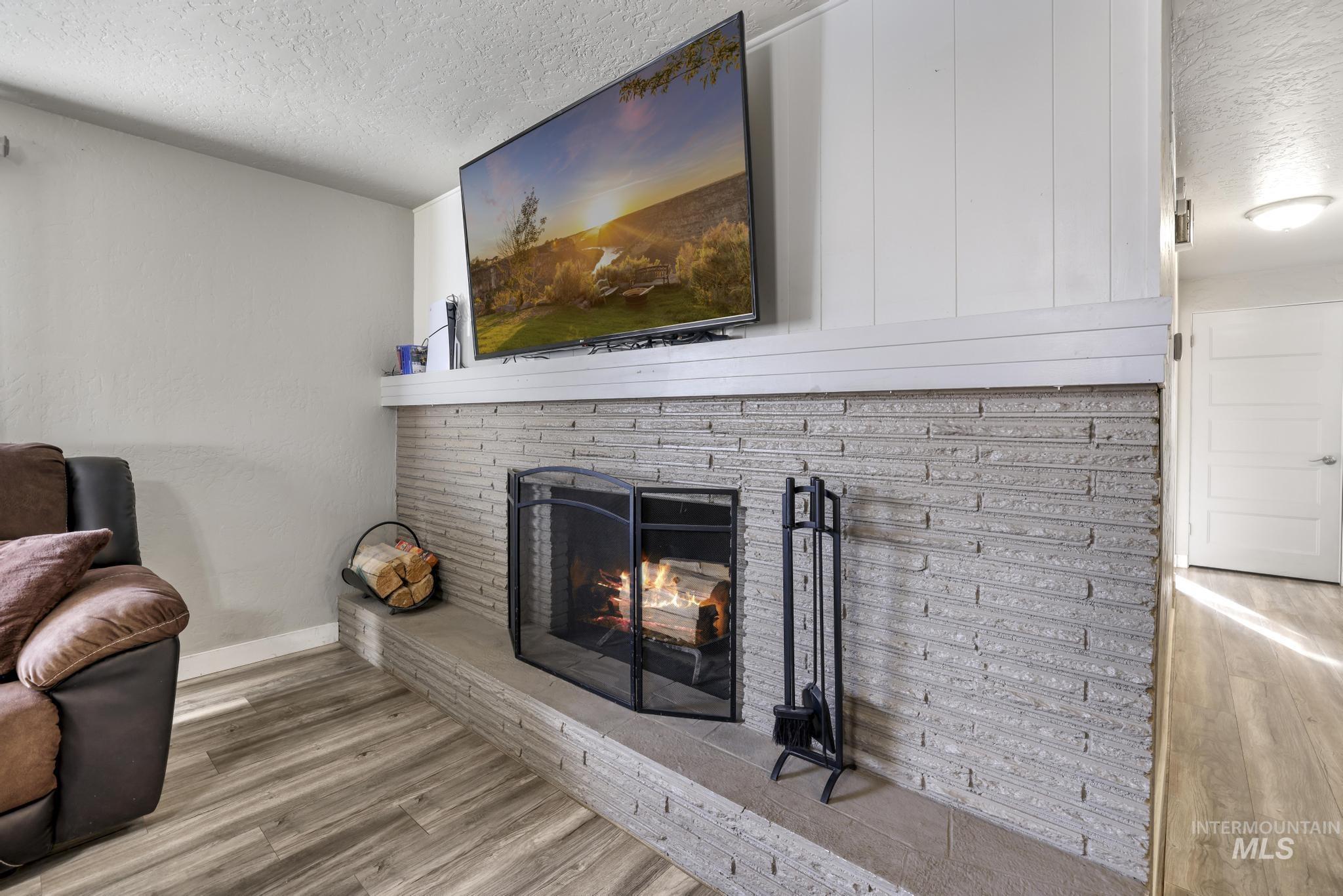 Detailed view of a textured ceiling, wood finished floors, and a fireplace