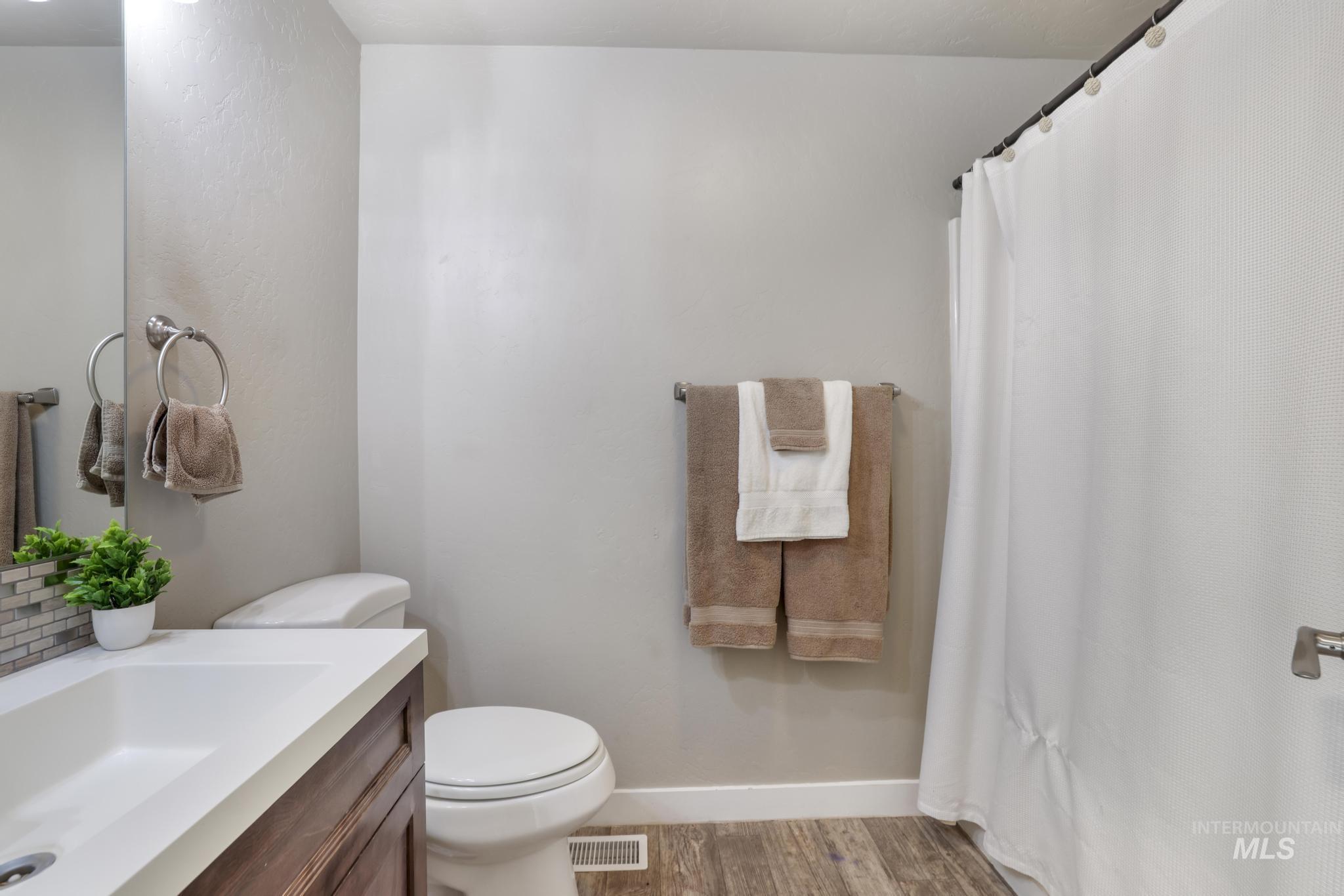 Full bath featuring curtained shower, vanity, and light wood-style floors