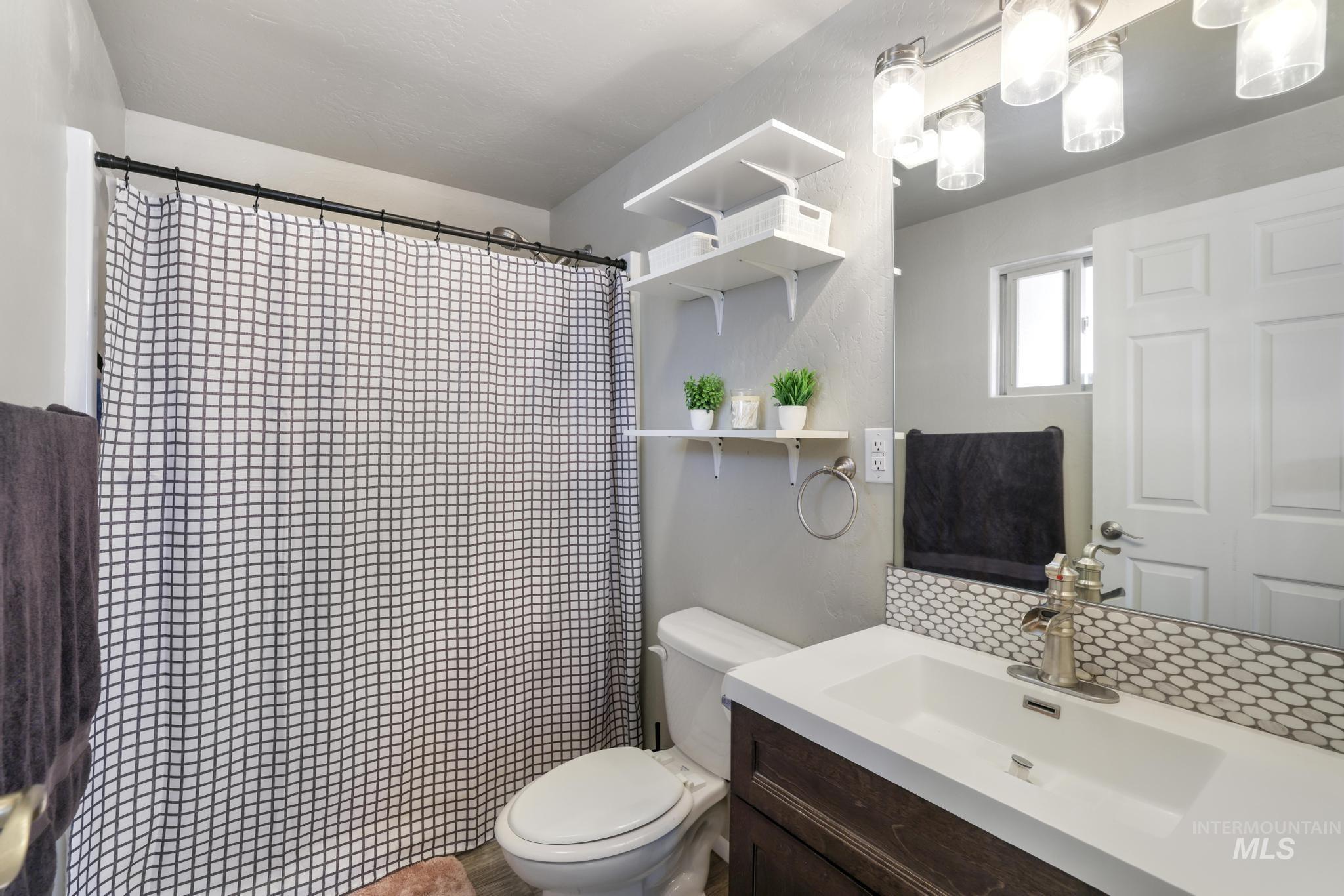 Full bathroom featuring curtained shower, vanity, and tasteful backsplash