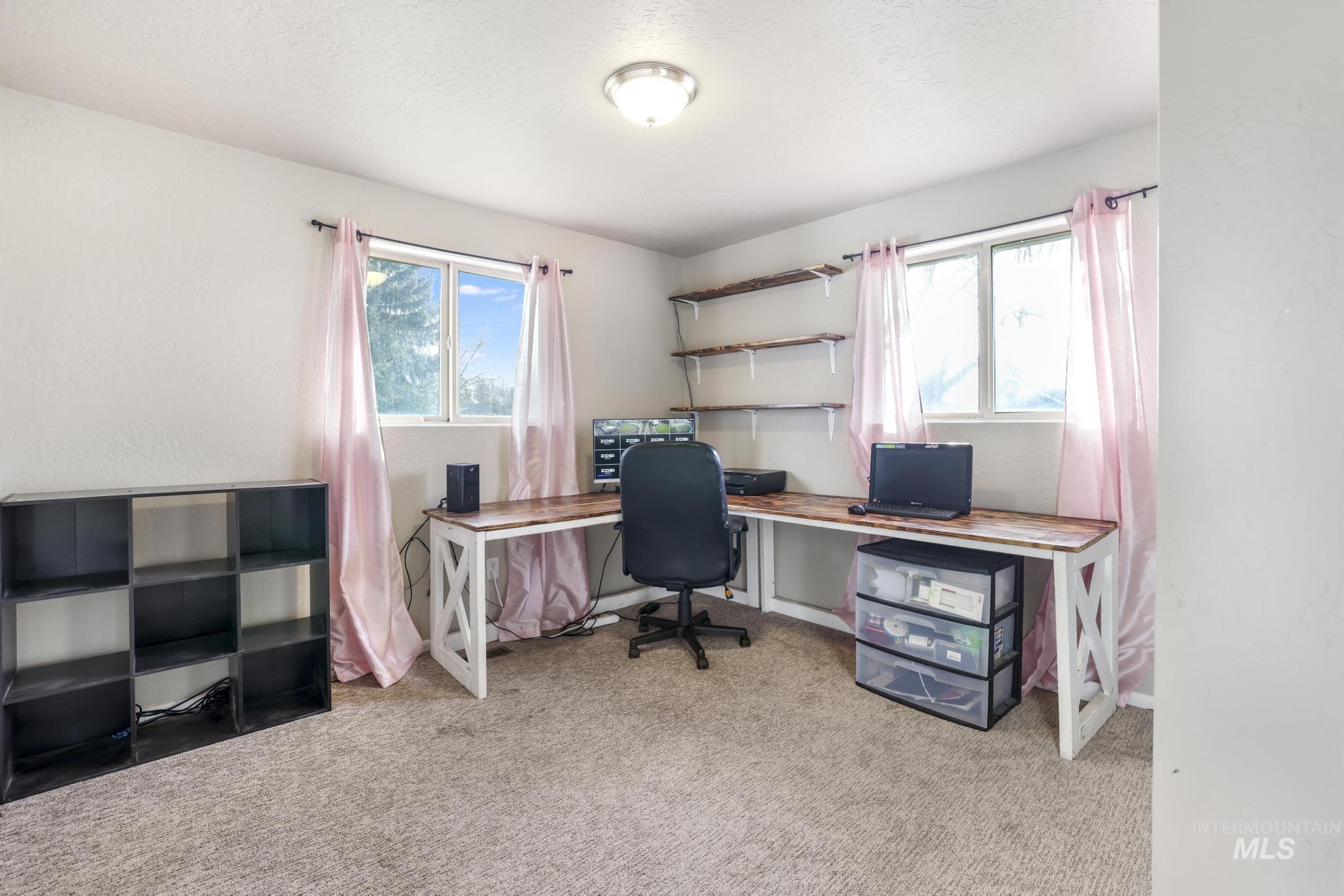 Office area with light carpet, plenty of natural light, and a textured ceiling