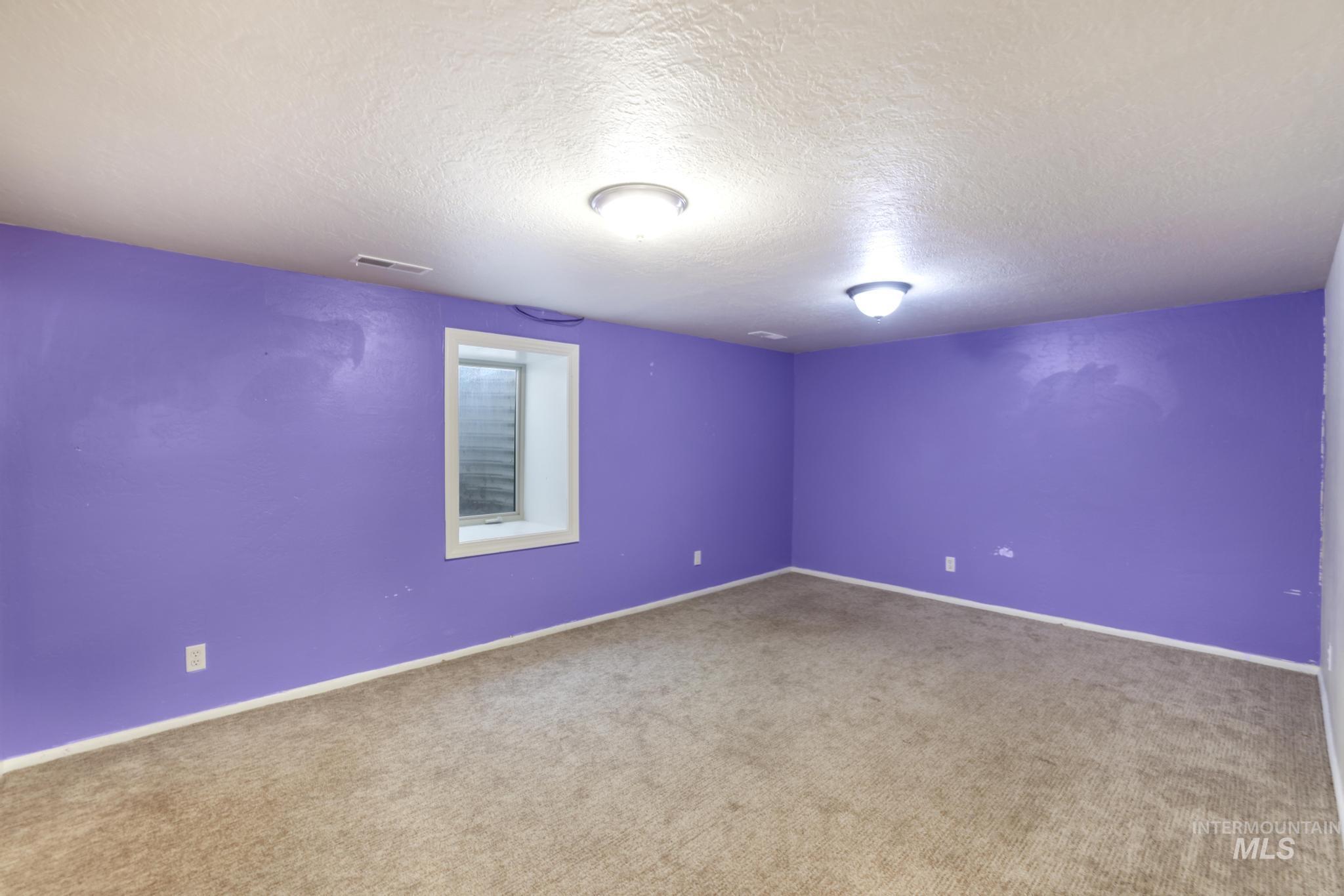 Unfurnished room featuring a textured ceiling and carpet flooring