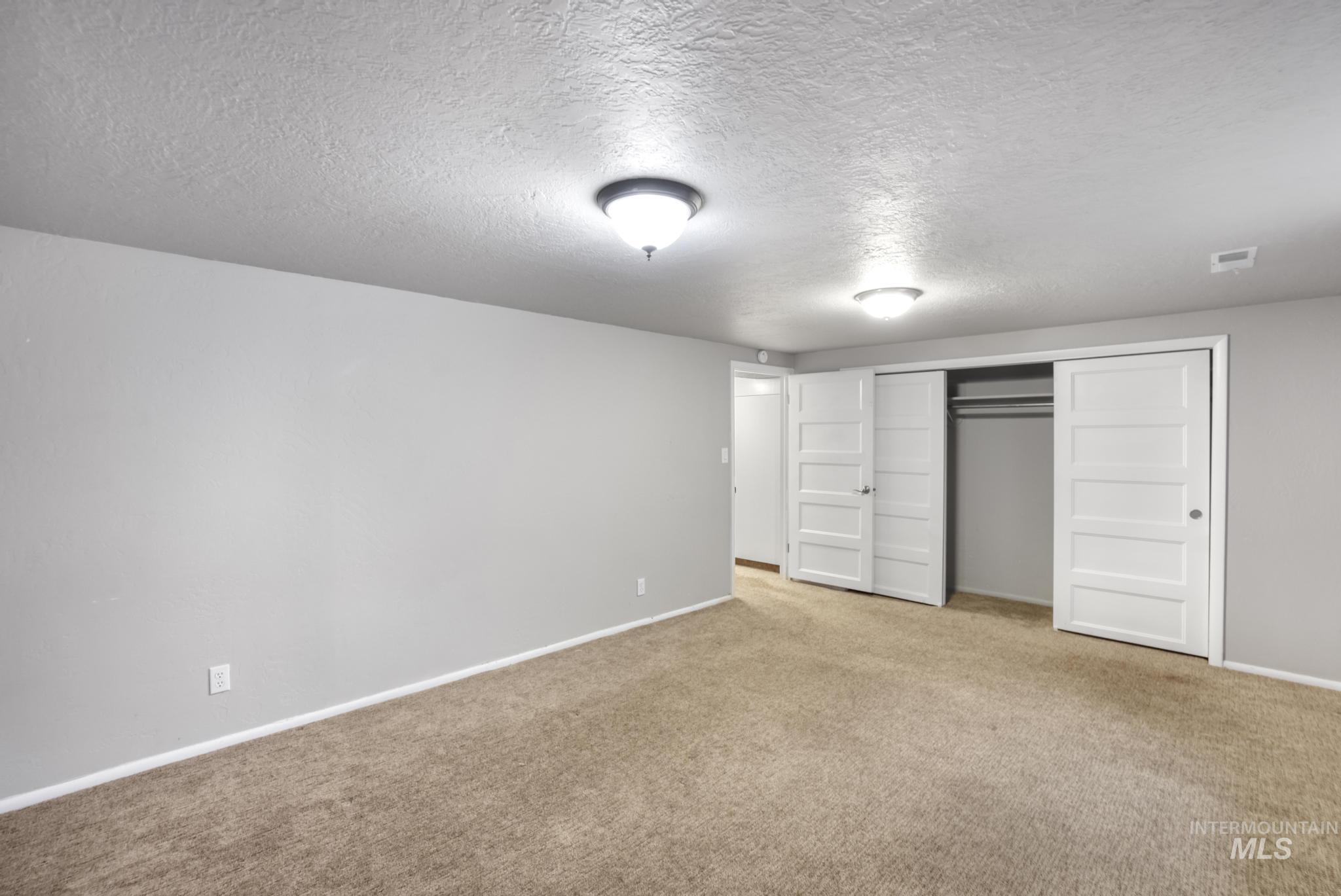 Unfurnished bedroom featuring a textured ceiling, a closet, and carpet