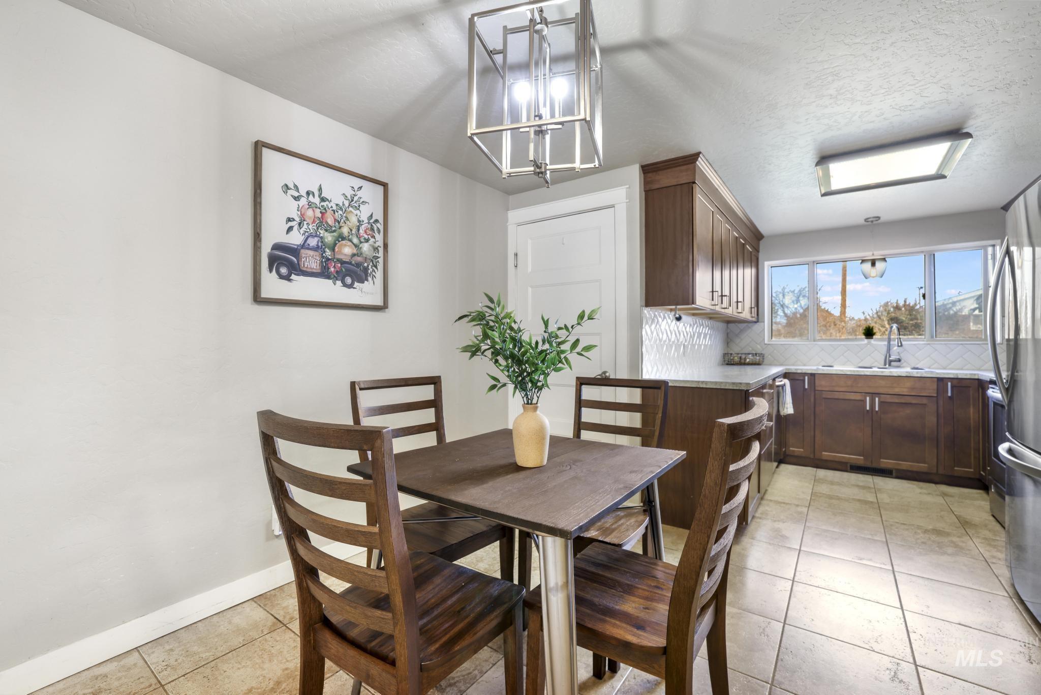 Dining space featuring a textured ceiling, light tile patterned floors, and a chandelier