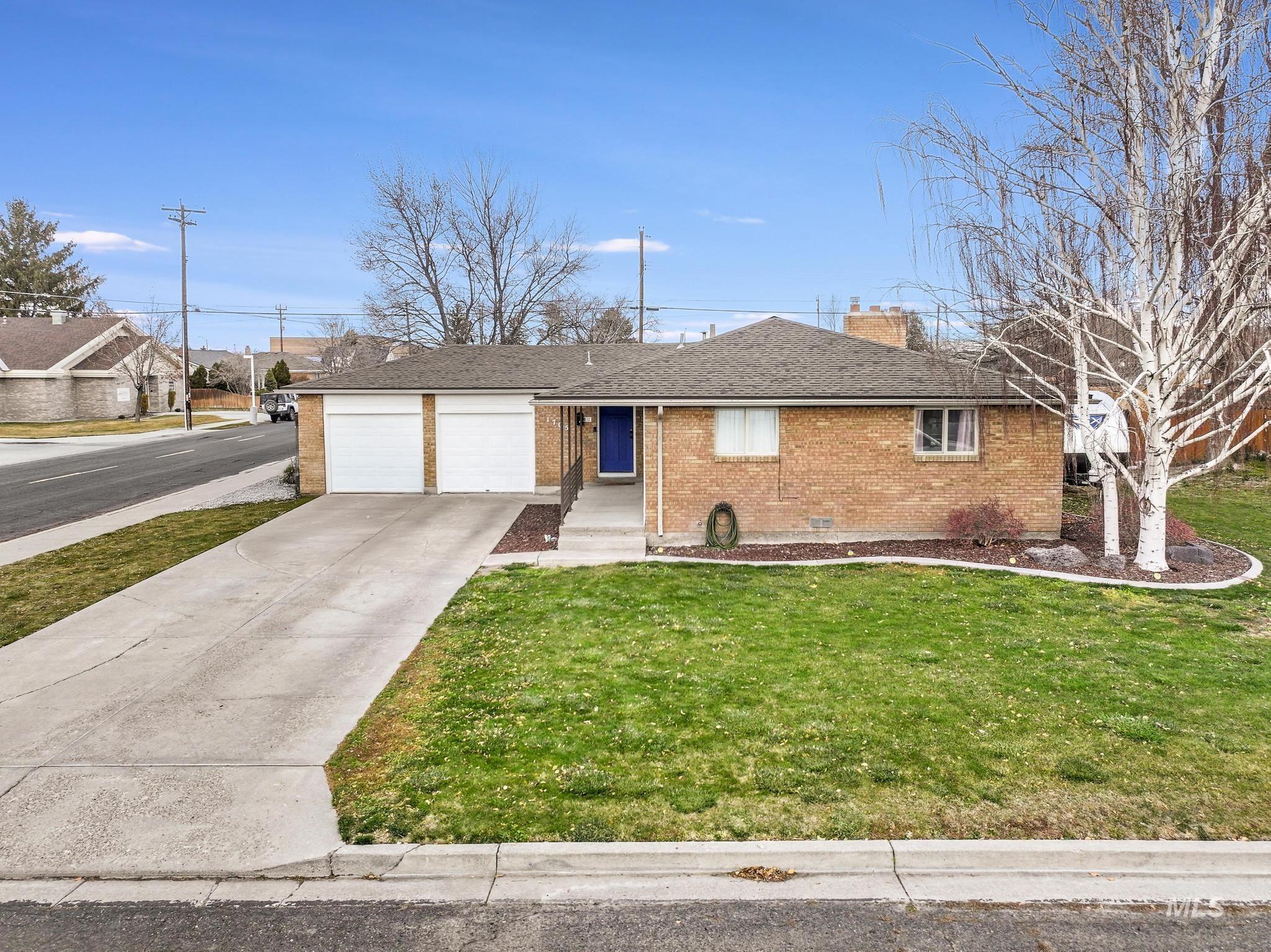 Ranch-style house featuring brick siding, concrete driveway, a front yard, a chimney, and an attached garage