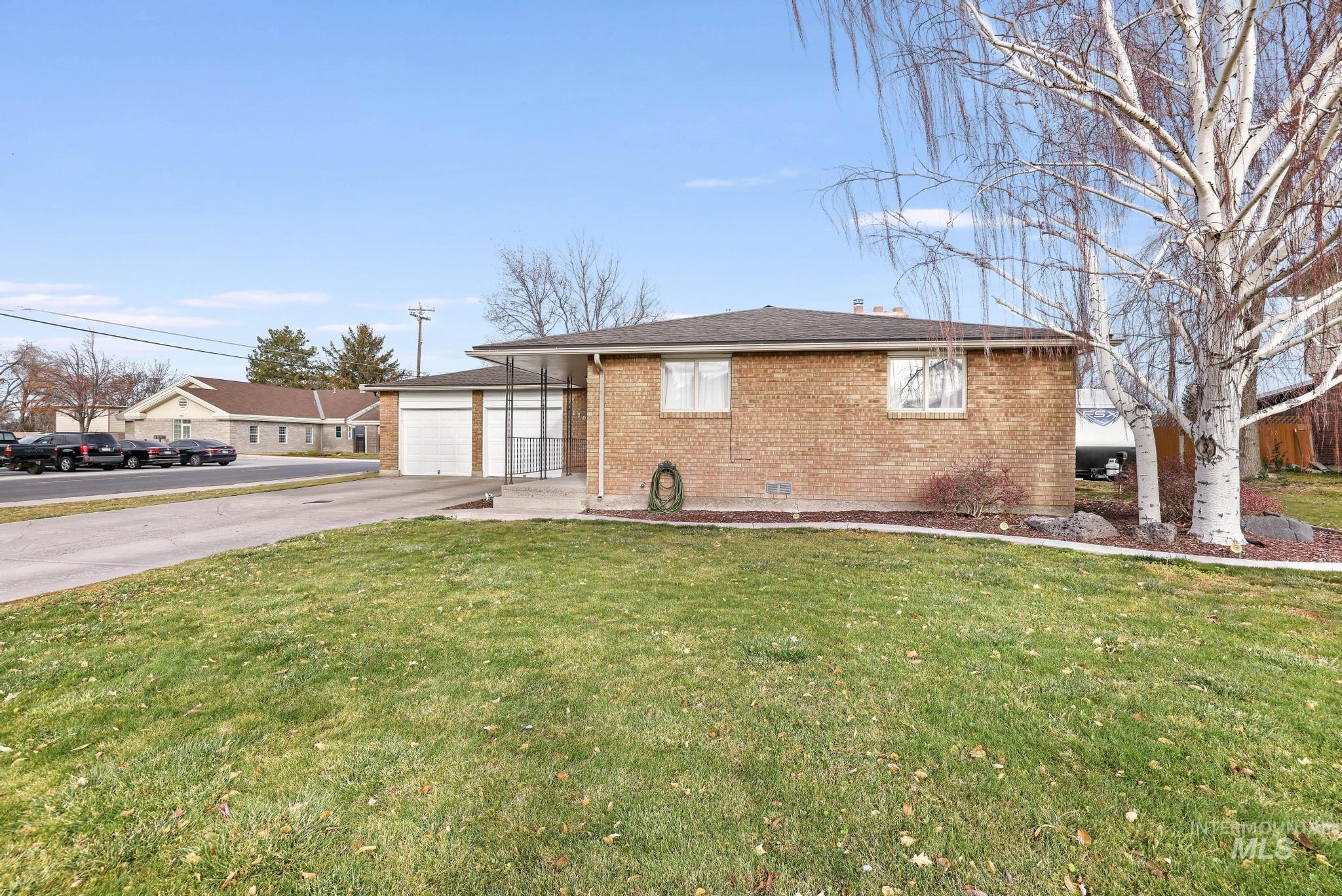 Ranch-style home featuring brick siding, a front yard, concrete driveway, and roof with shingles