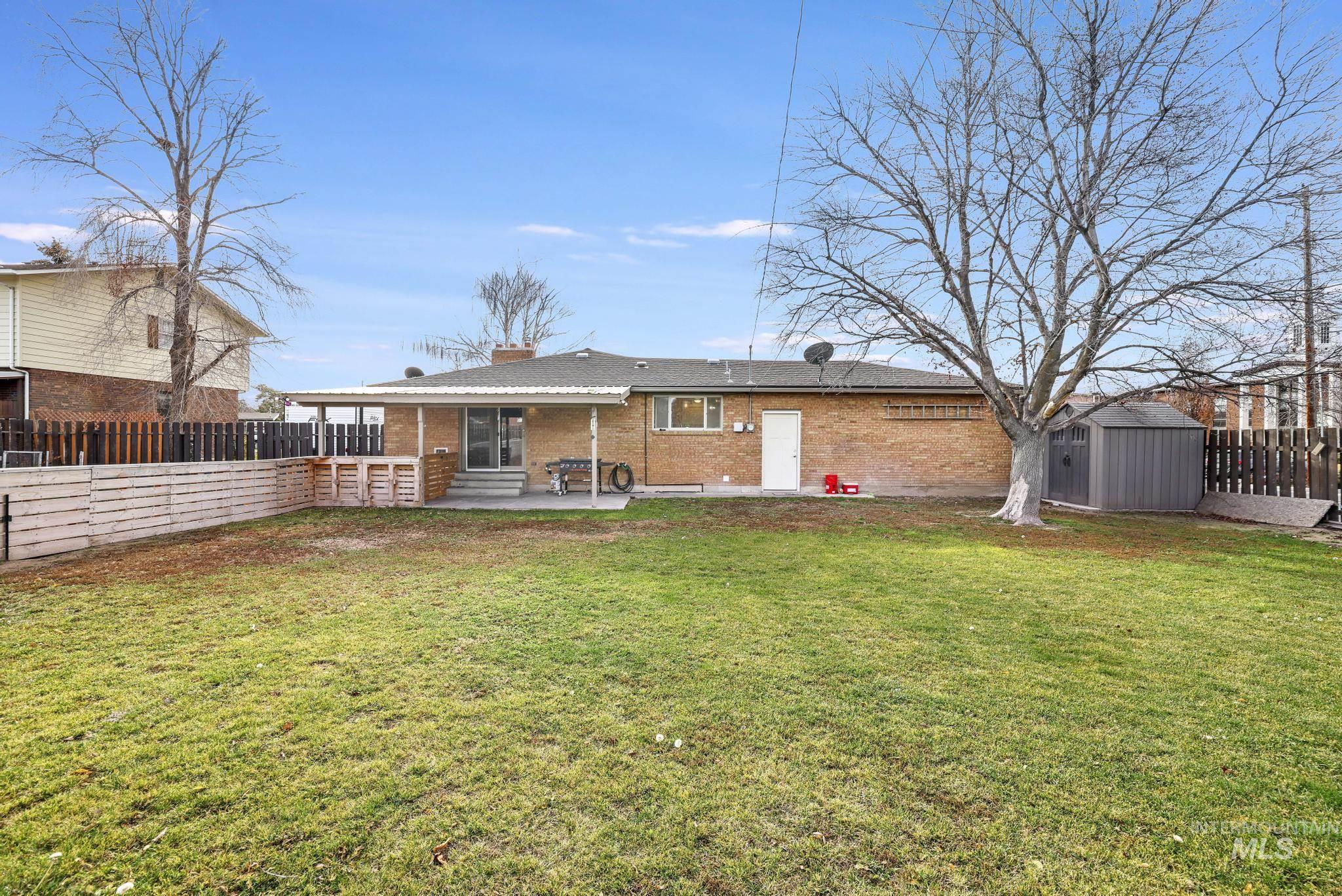 Back of property with a shed, brick siding, a fenced backyard, a patio, and a chimney