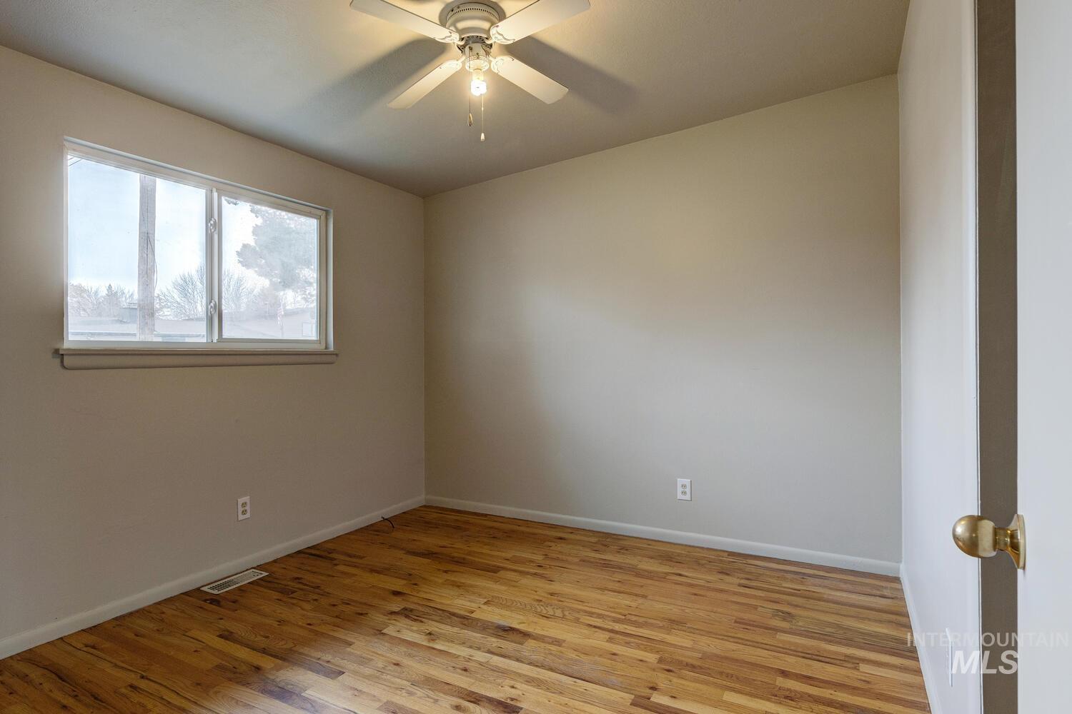 Empty room with light wood-style floors and a ceiling fan