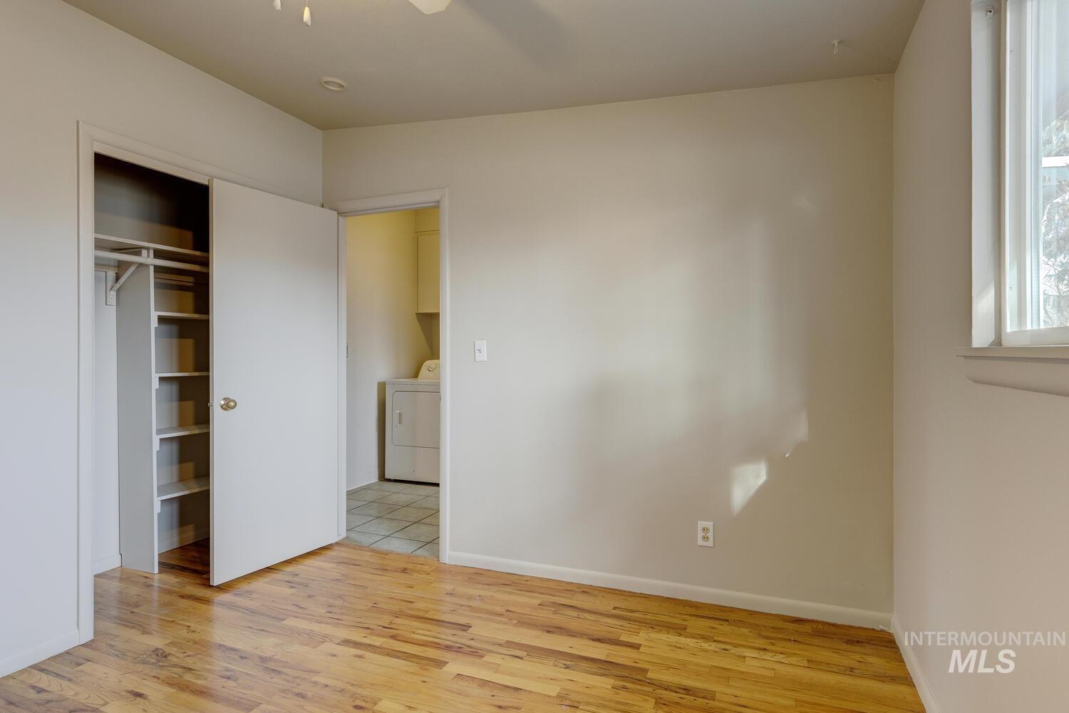 Unfurnished bedroom with light wood-style floors, a ceiling fan, and a closet