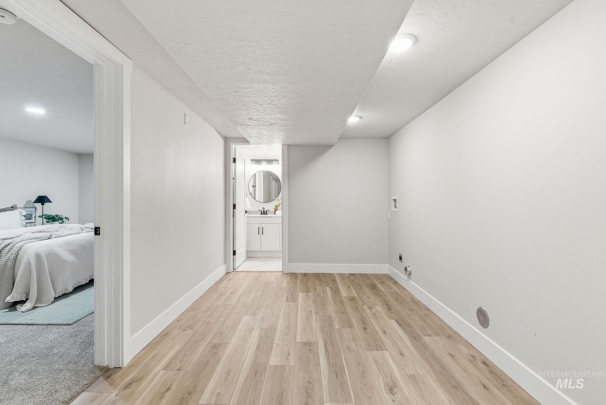 Finished below grade area with a textured ceiling, light wood-style flooring, and recessed lighting