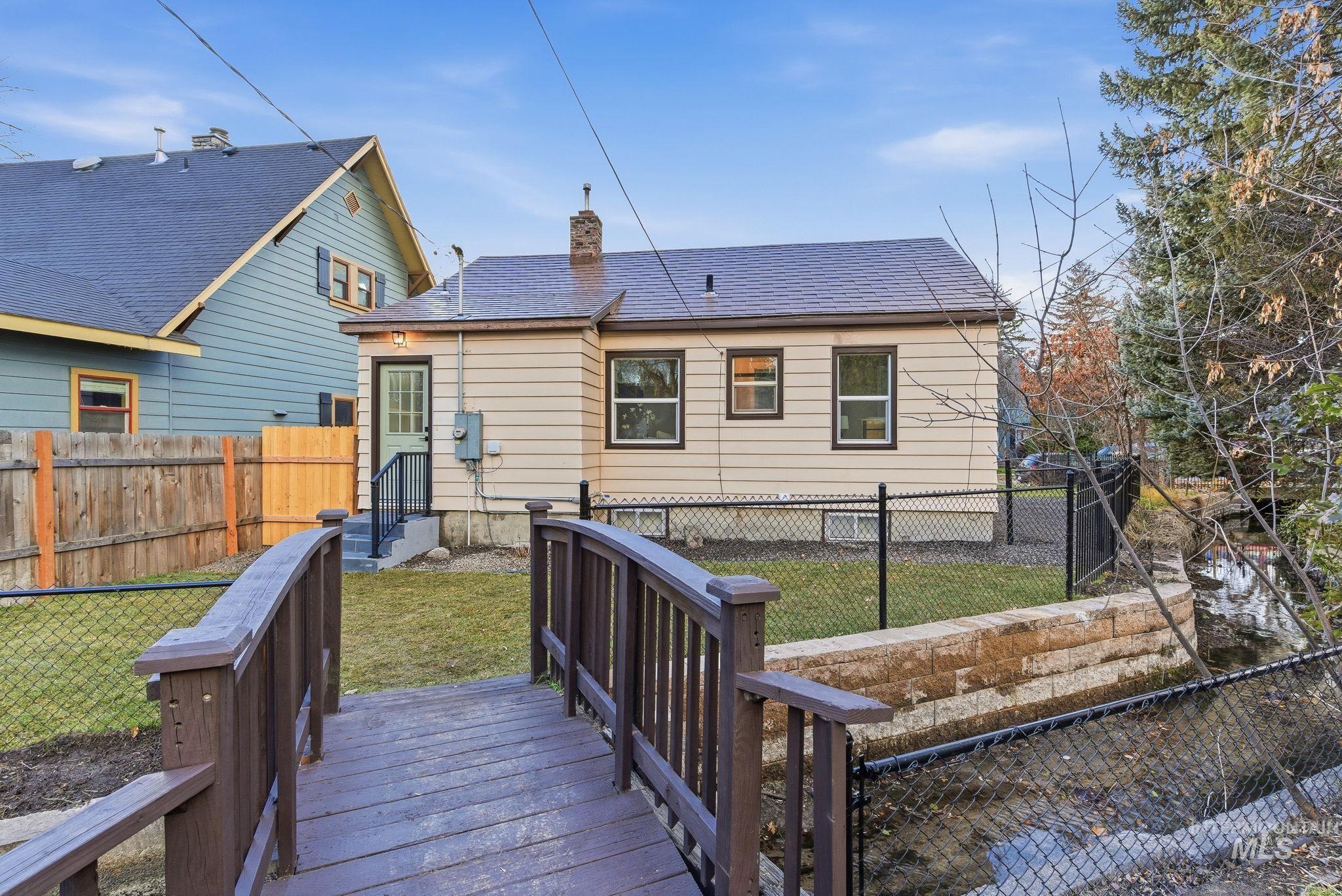 Back of house featuring a fenced backyard, a chimney, roof with shingles, and a deck
