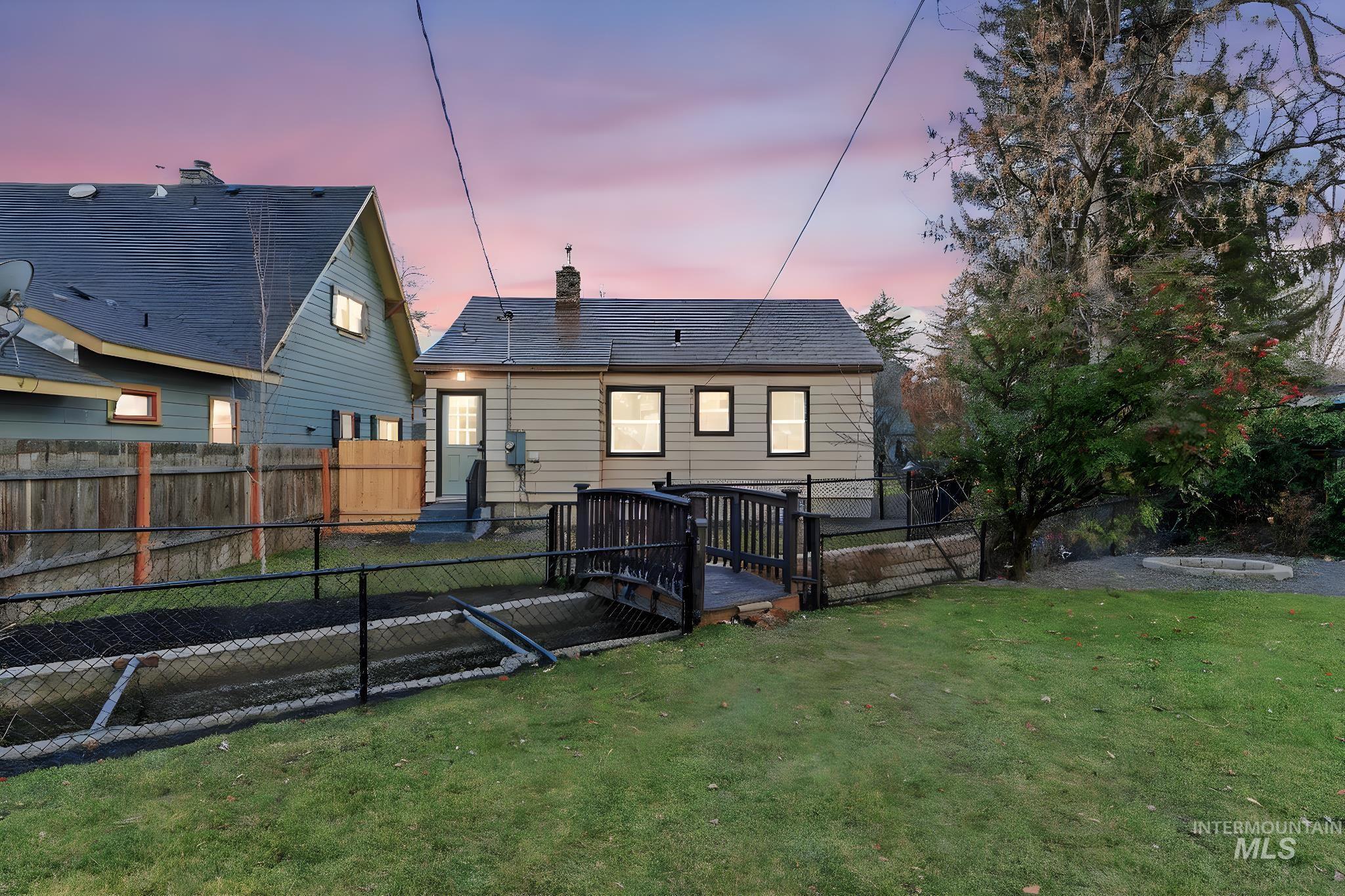Back of house at dusk with a wooden deck, a fenced backyard, and a chimney