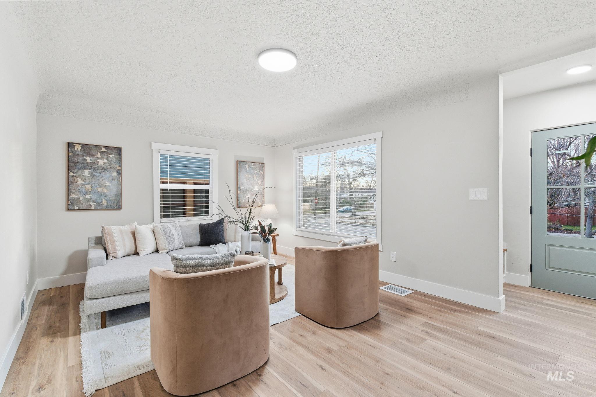 Living room with a textured ceiling and light wood-style flooring