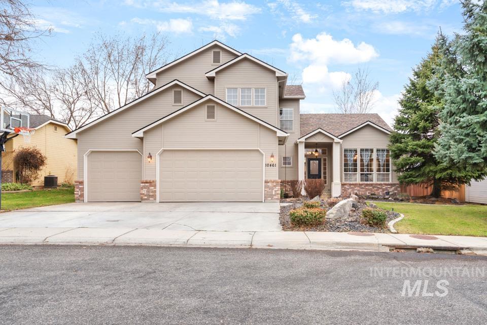 Traditional home featuring driveway, stone siding, a front yard, and a garage
