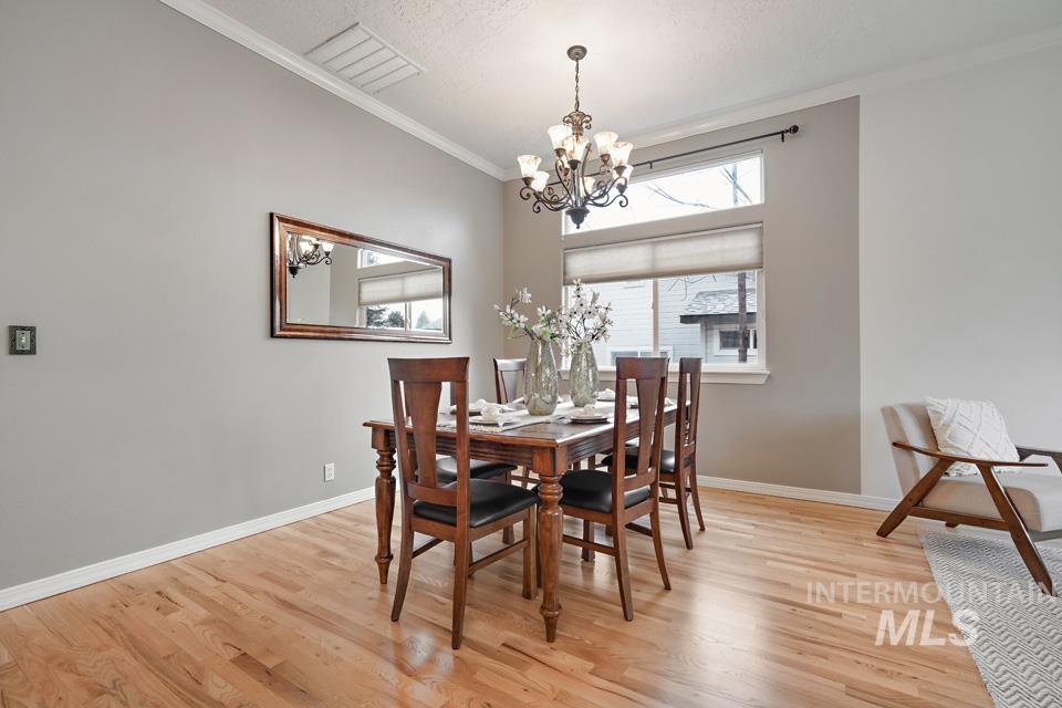 Dining room with crown molding, light wood-type flooring, and a chandelier