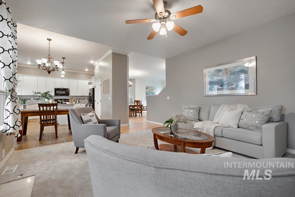 Living room with a ceiling fan, a chandelier, light tile patterned floors, and crown molding