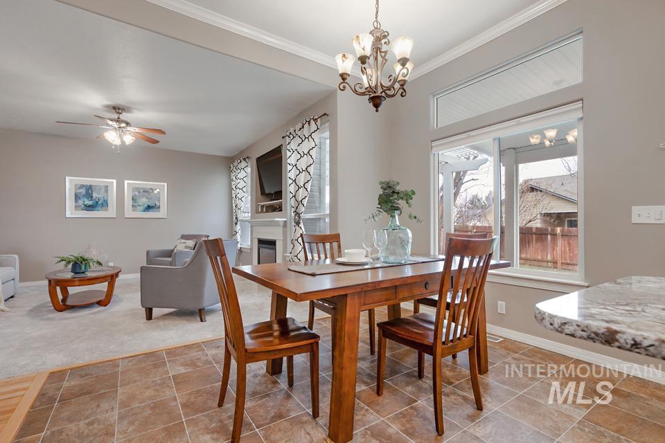 Dining area featuring a glass covered fireplace, a ceiling fan, ornamental molding, and a chandelier