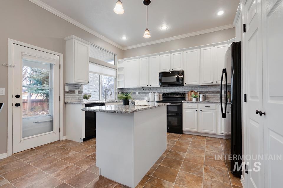 Kitchen featuring white cabinetry, backsplash, black appliances, light stone counters, and ornamental molding