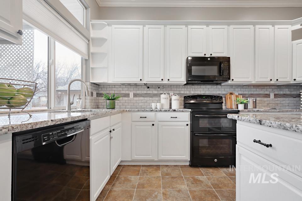 Kitchen with white cabinetry, black appliances, open shelves, light stone counters, and decorative backsplash