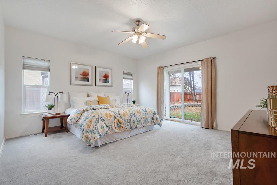 Carpeted bedroom featuring multiple windows and a ceiling fan
