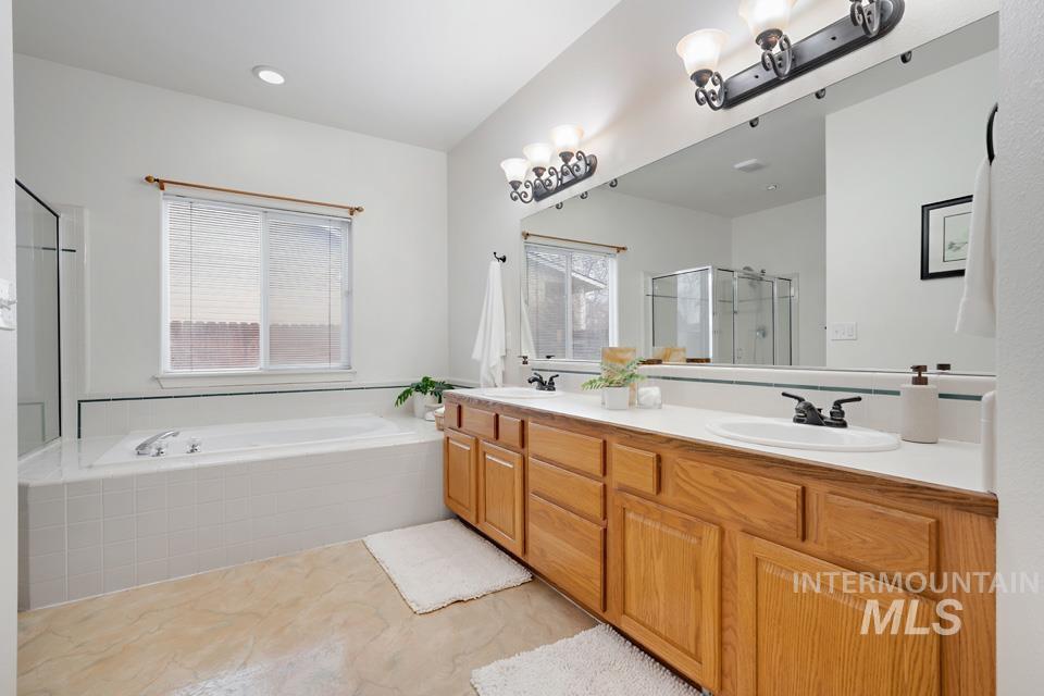 Full bathroom featuring double vanity, a bath, and a stall shower