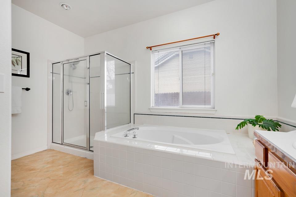 Bathroom with a garden tub, a stall shower, vanity, and light tile patterned flooring