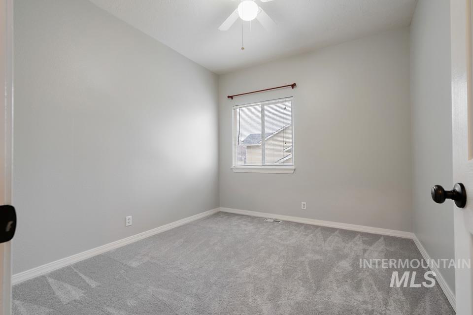 Carpeted spare room with baseboards and ceiling fan
