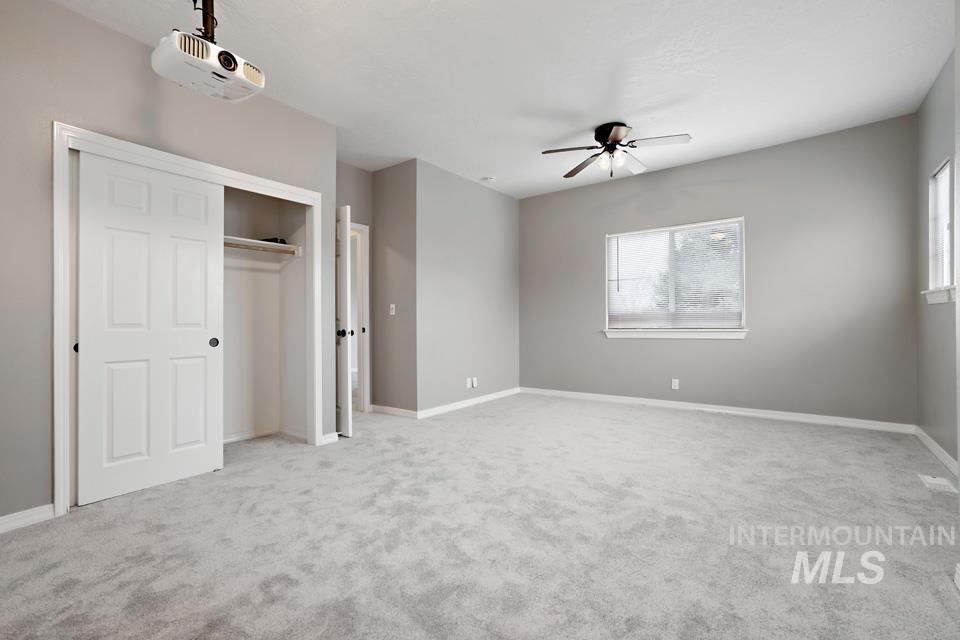 Unfurnished bedroom with a closet, light carpet, and a ceiling fan