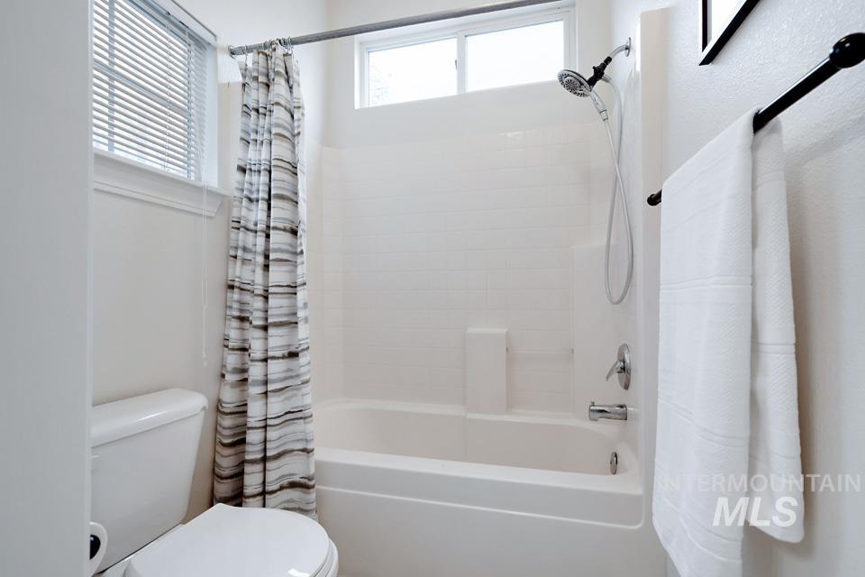 Full bath featuring shower / bath combination with curtain and plenty of natural light
