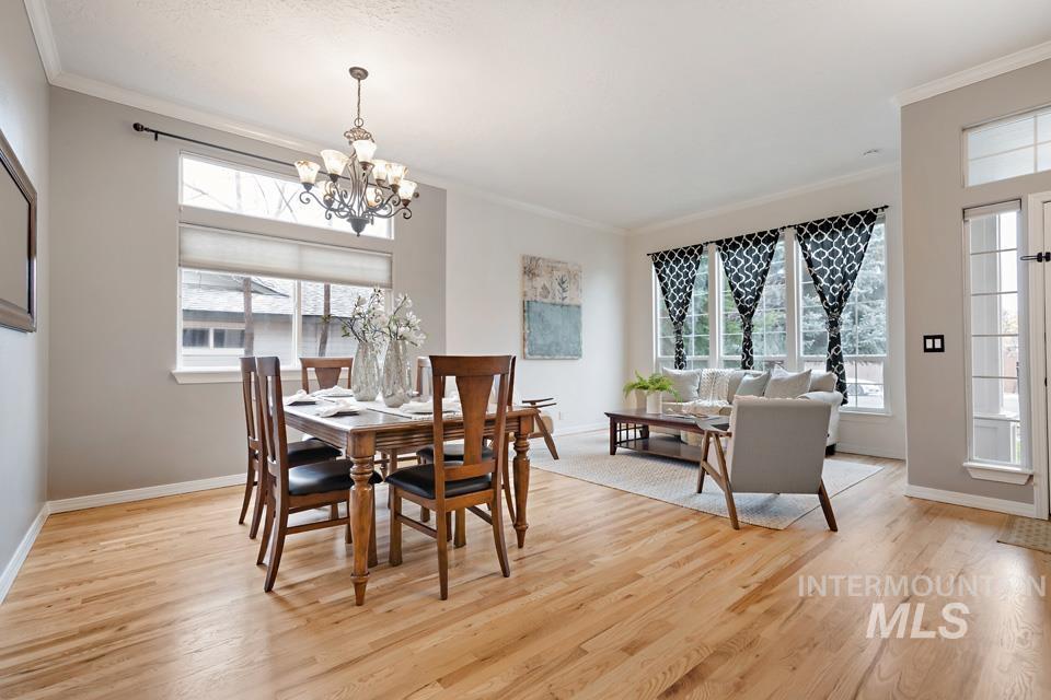 Dining room with crown molding, light wood-type flooring, healthy amount of natural light, and a chandelier