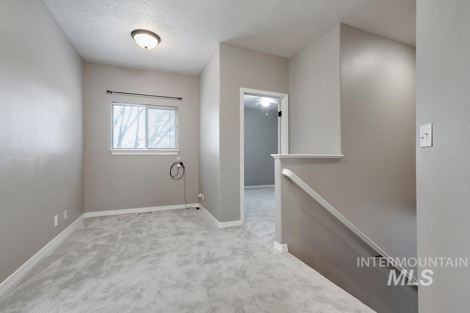 Empty room with light carpet and a textured ceiling