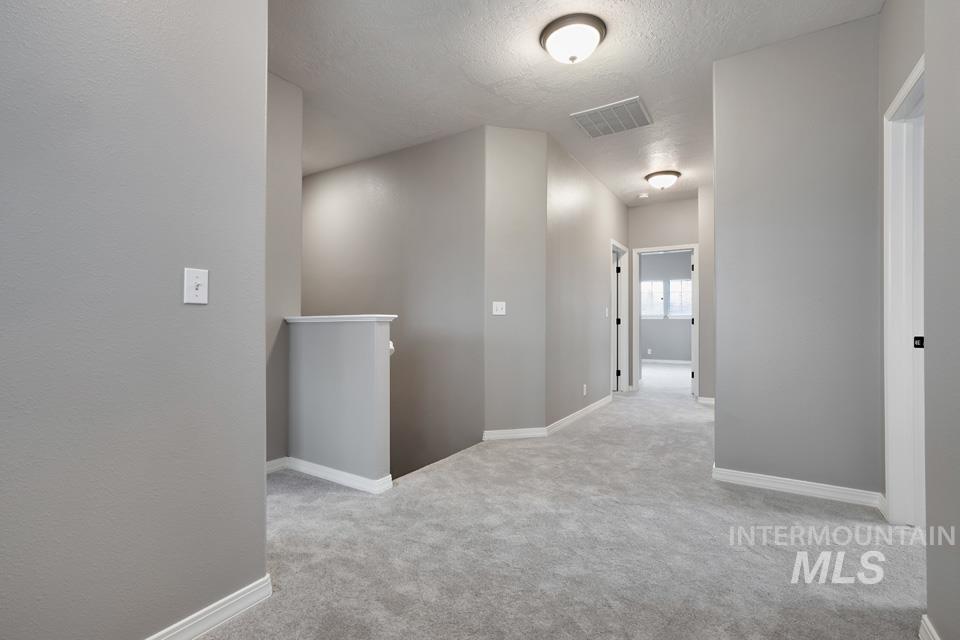 Hall featuring an upstairs landing, a textured ceiling, and carpet