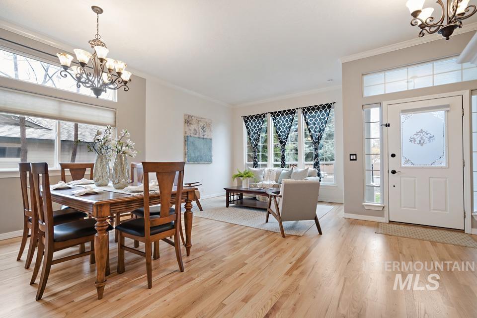 Dining room with a chandelier, healthy amount of natural light, ornamental molding, and light wood-style flooring