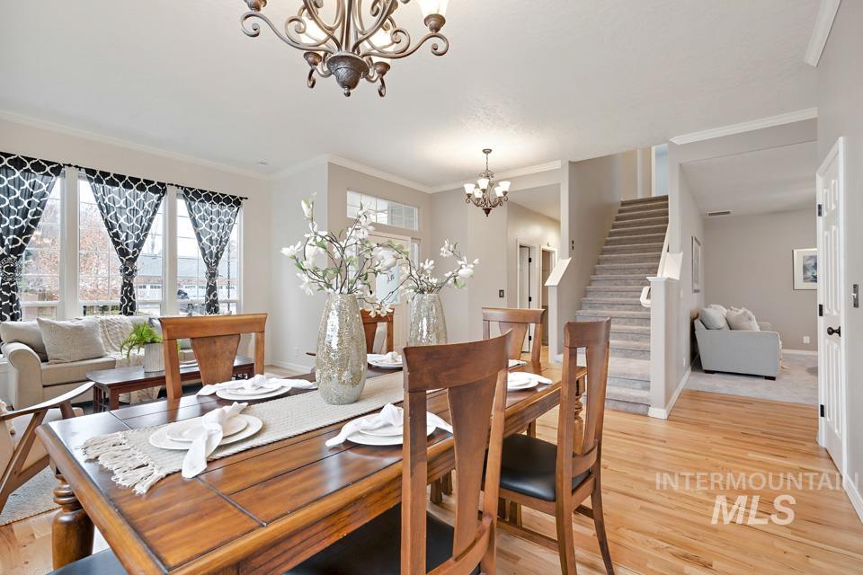 Dining room featuring light wood finished floors, ornamental molding, stairs, and a chandelier