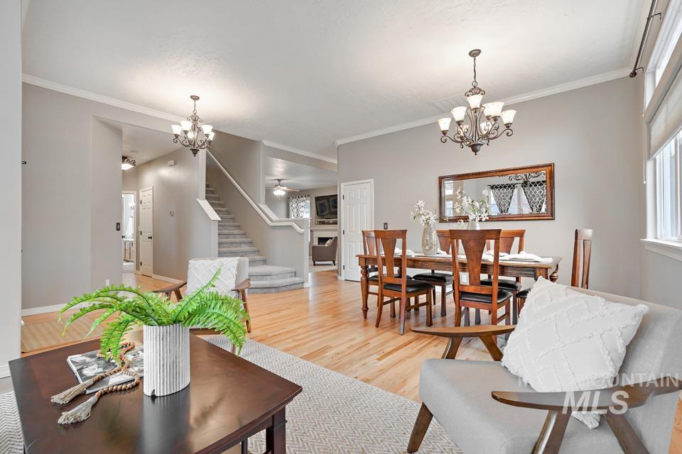 Living area featuring a chandelier, stairs, wood finished floors, and ornamental molding
