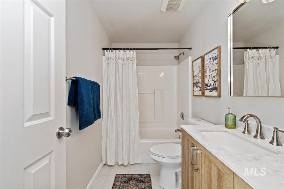 Bathroom with shower / bathtub combination with curtain, vanity, and light tile patterned floors