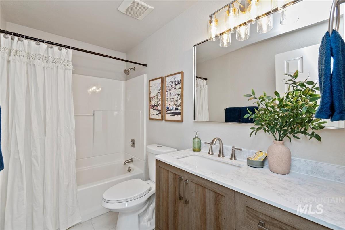 Bathroom with vanity, shower / bathtub combination with curtain, a chandelier, and light tile patterned floors