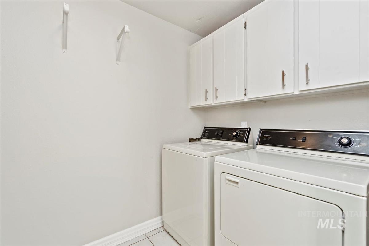 Laundry area featuring independent washer and dryer, cabinet space, and light tile patterned floors