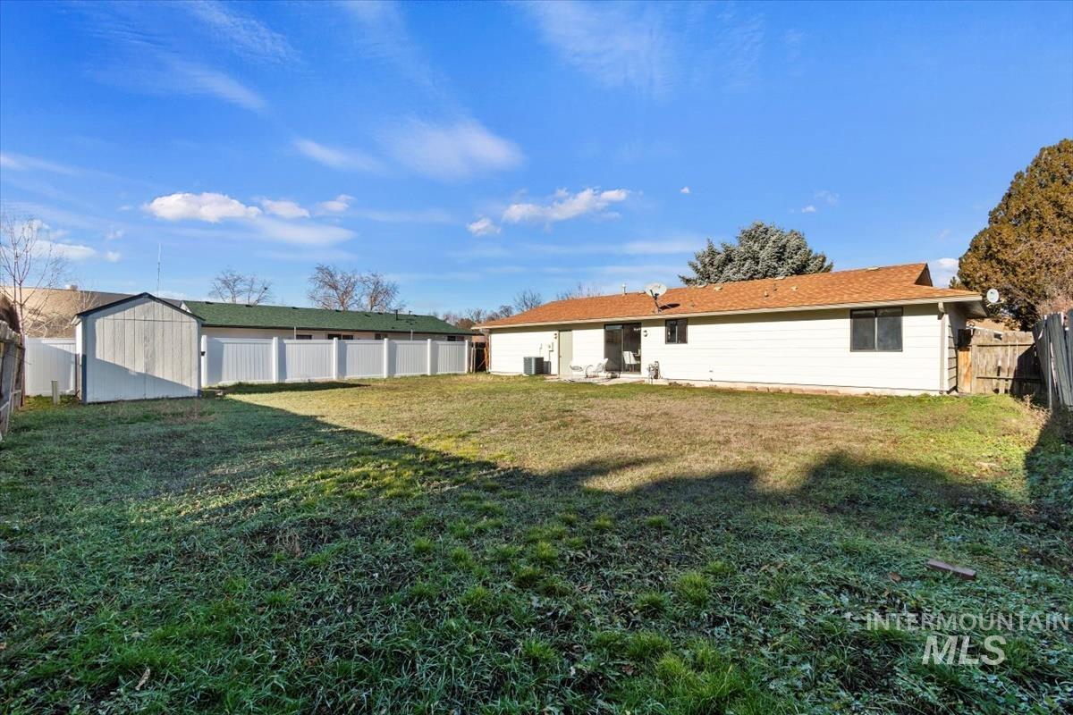 Rear view of property featuring a fenced backyard, a patio area, and a shed