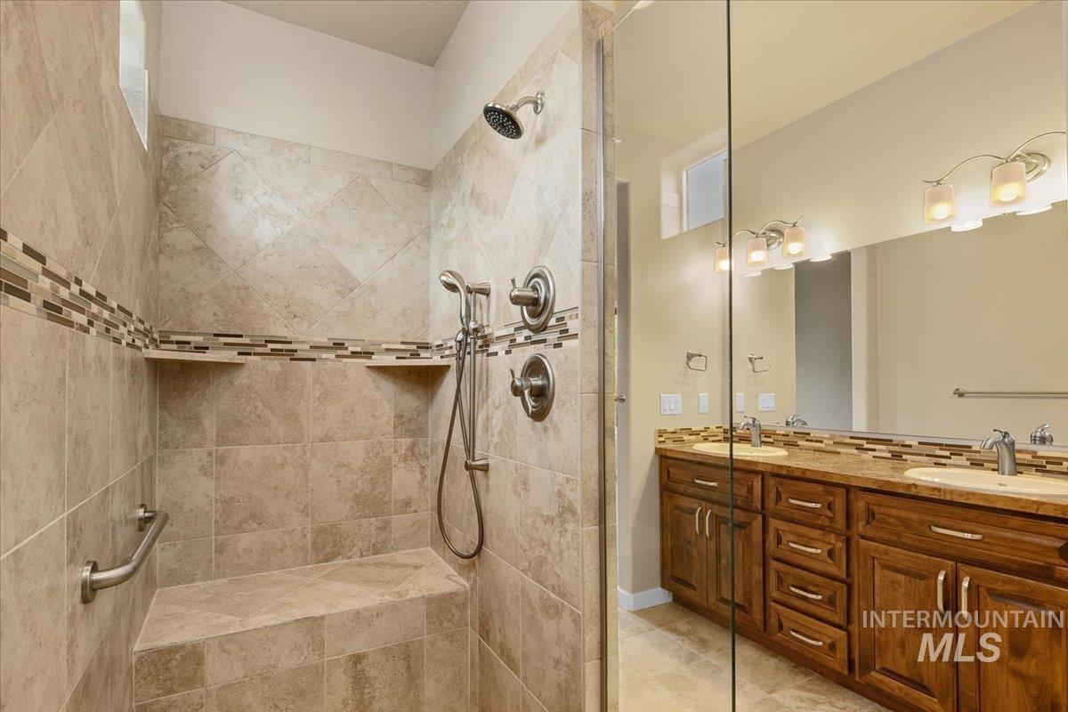 Primary Bathroom with double vanity, a tile shower, and heated light tile flooring