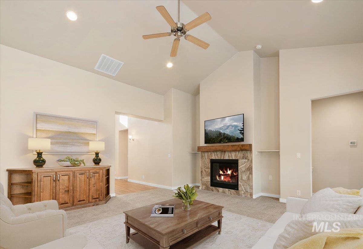 Living room featuring light carpet, a tiled fireplace, high vaulted ceiling, ceiling fan, and recessed lighting