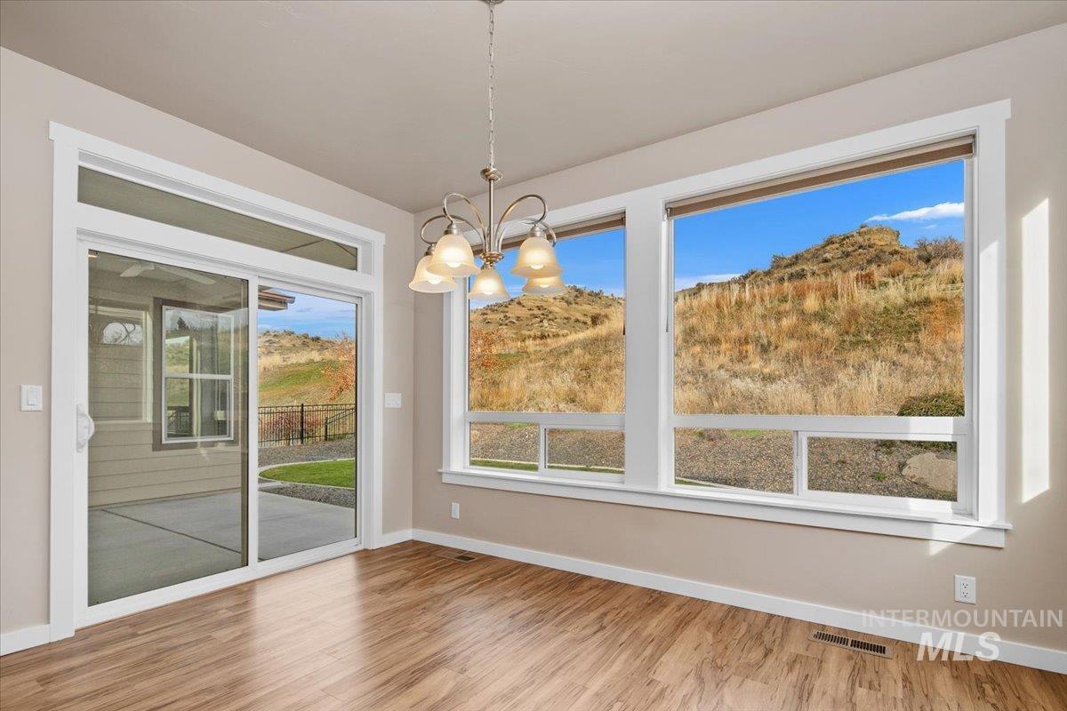 Unfurnished dining area featuring wood finished floors and a chandelier