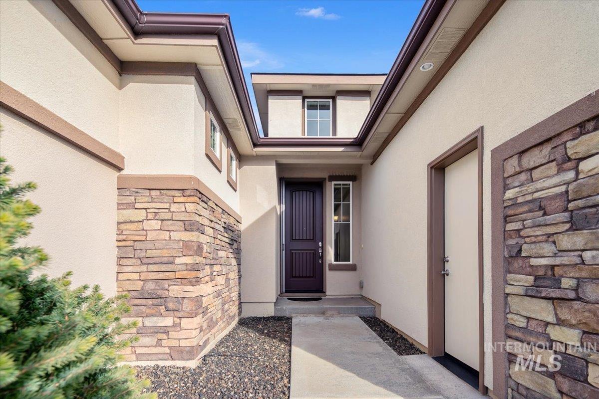 Entrance to property with stone siding and stucco siding