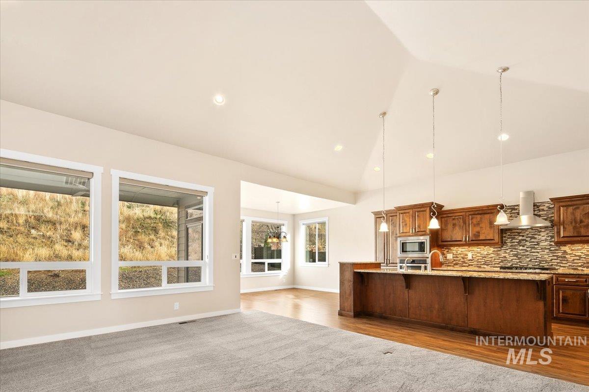 Kitchen with hanging light fixtures, a chandelier, open floor plan, an island with sink, and a kitchen bar