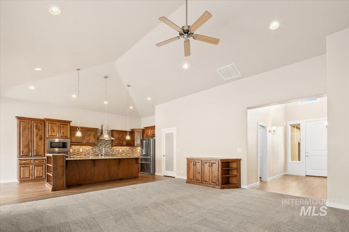 Kitchen with open floor plan, high vaulted ceiling, a breakfast bar, a large island, and stainless steel appliances