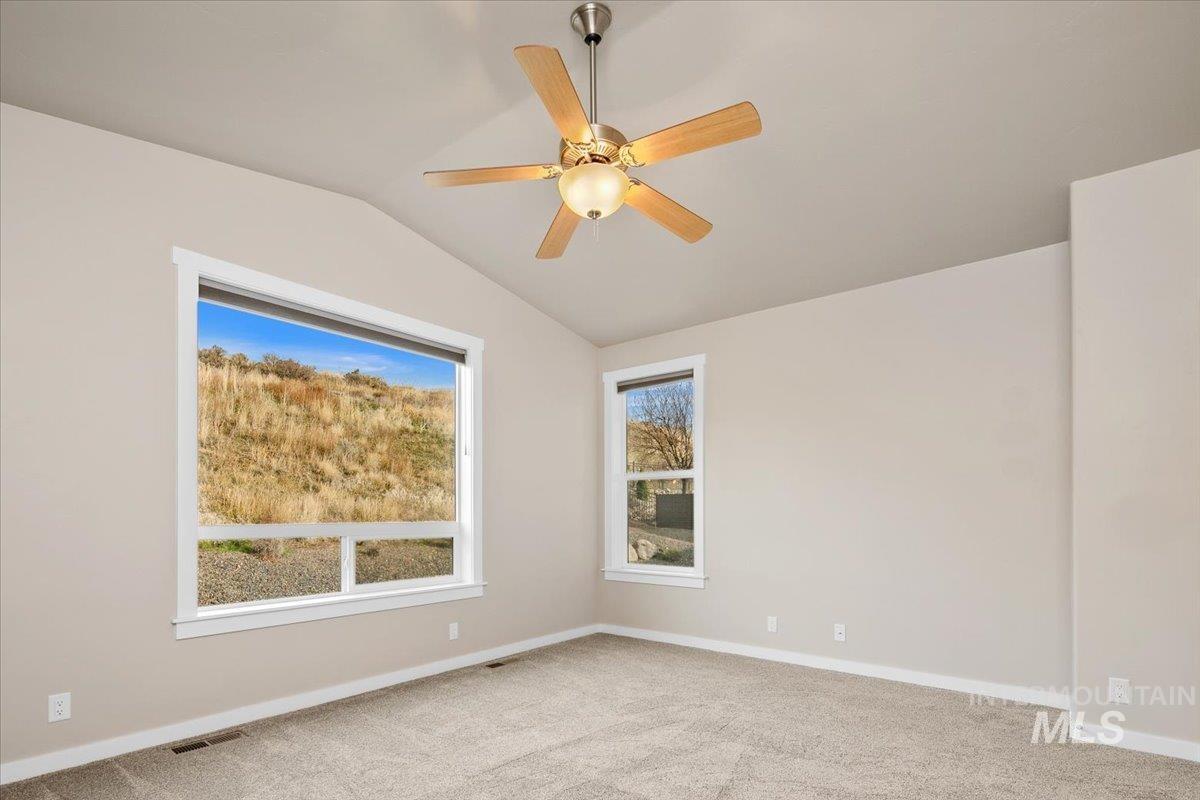 Carpeted spare room featuring lofted ceiling and a ceiling fan